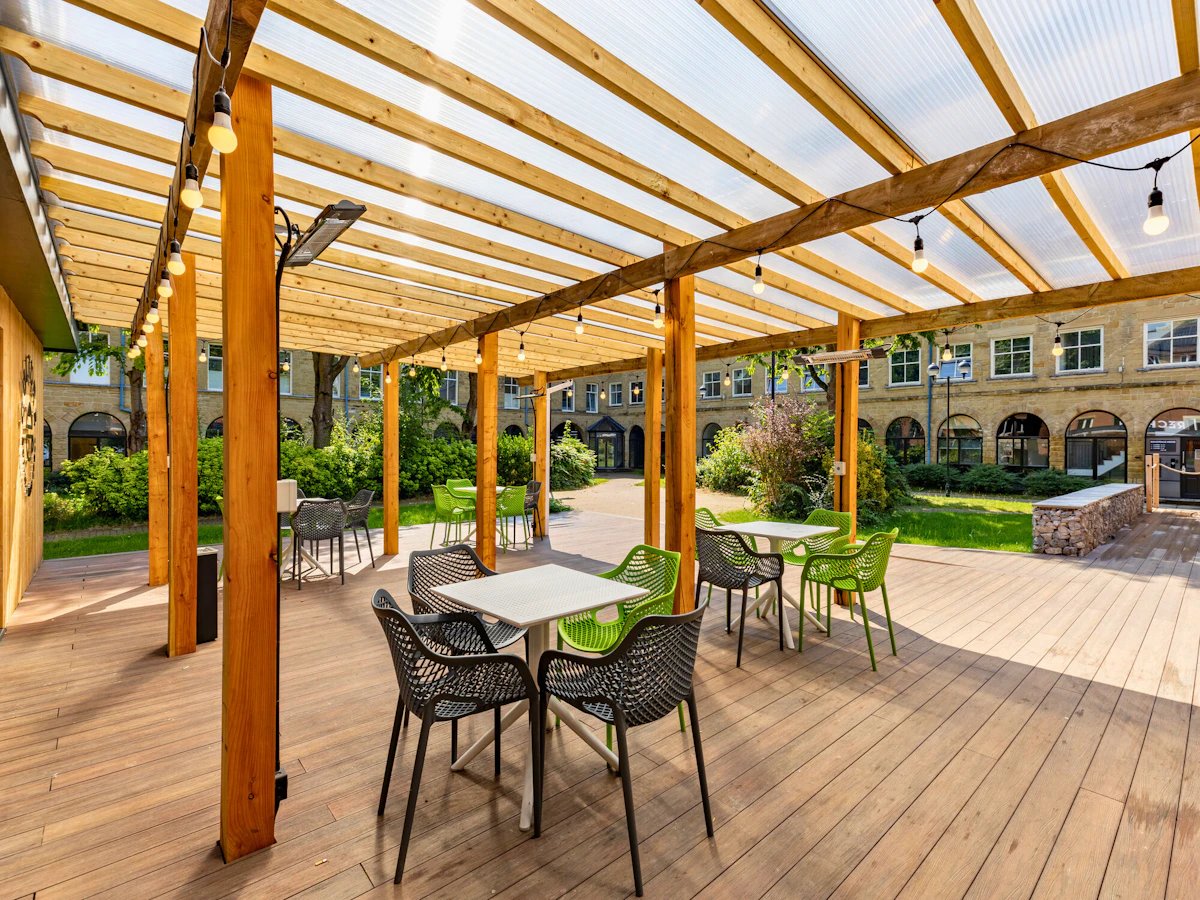 Wooden pergola with tables chairs and lighting outdoor area at The Leather Works in Leeds Student Accommodation