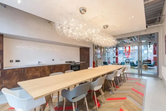 Communal table chairs kitchen area and lounge at Livin Cardiff in Cardiff Student Accommodation
