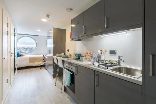 Modern kitchen area with bed and round window bedroom at Livin Cardiff in Cardiff Student Accommodation