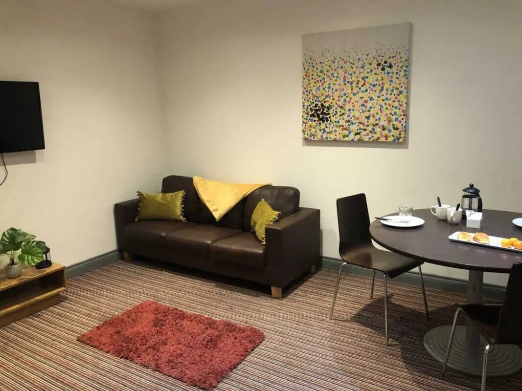 Brown couch art table chairs rug living room at Norflok Street in Sunderland Student Accommodation
