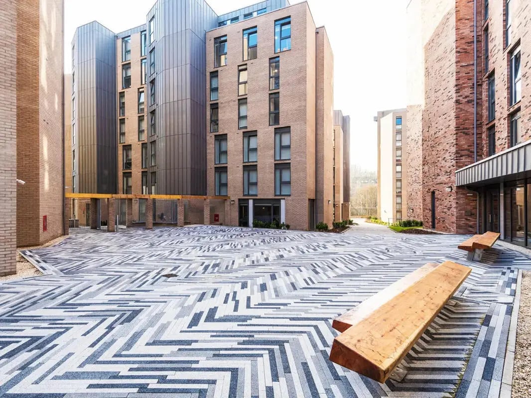 Modern buildings with patterned courtyard and benches exterior at Dunaskin Mill in Glasgow Student Accommodation