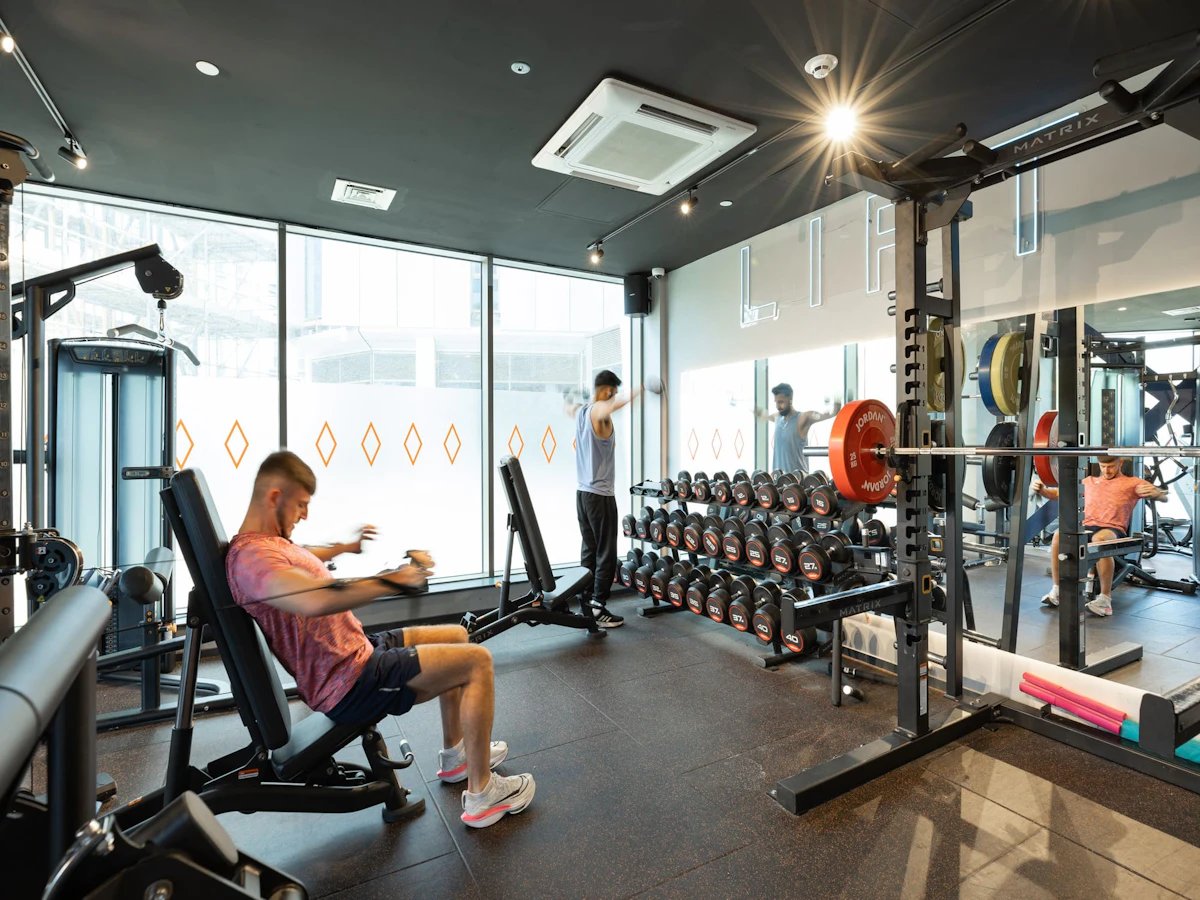 Weight racks dumbbells people exercising gym area at Limelight in Liverpool Student Accommodation