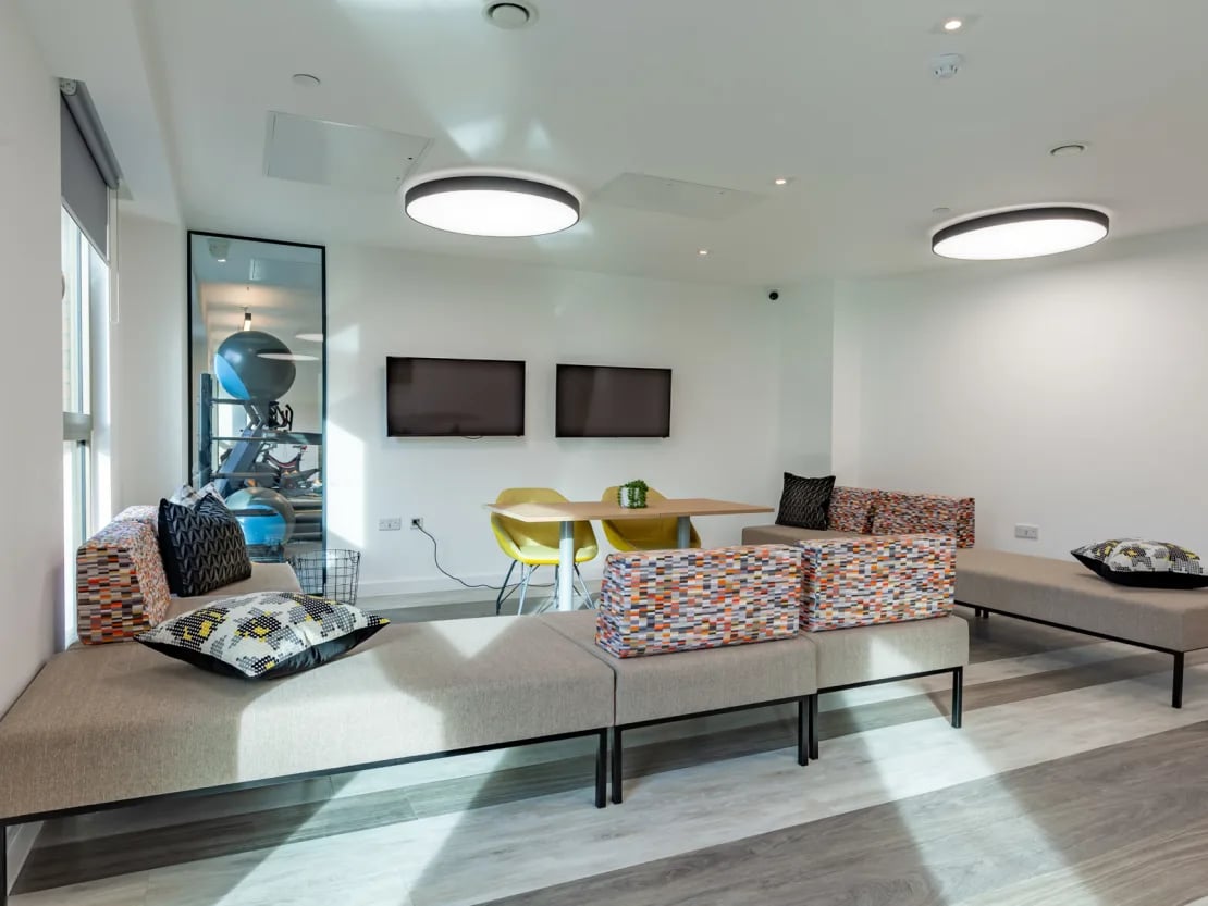 Modern lounge with sofas dining table and TVs living room at Pavilion Point in Brighton Student Accommodation