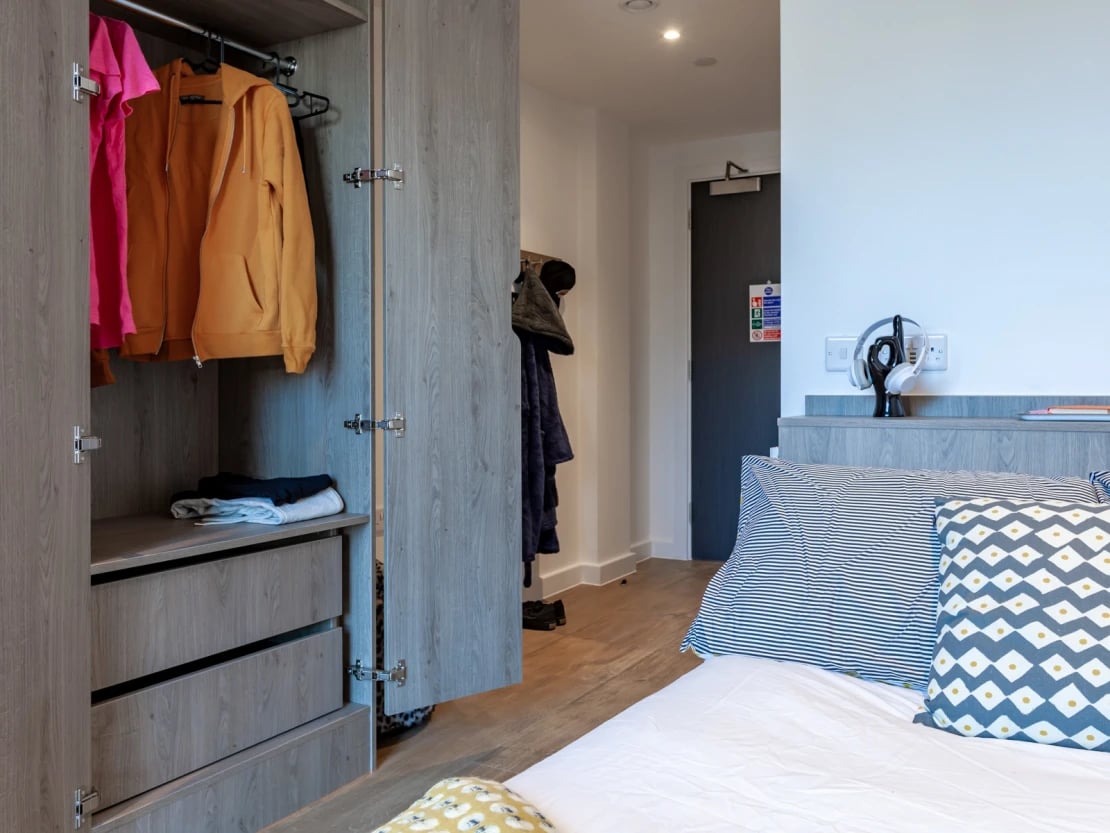 Wardrobe with clothes and bed with pillows bedroom at Pavilion Point in Brighton Student Accommodation