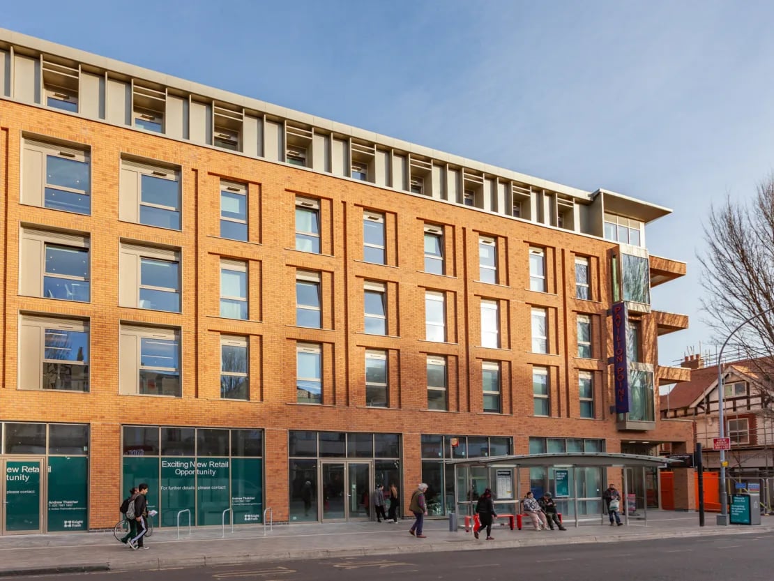 Modern brick building with large windows and bus stop exterior at Pavilion Point in Brighton Student Accommodation