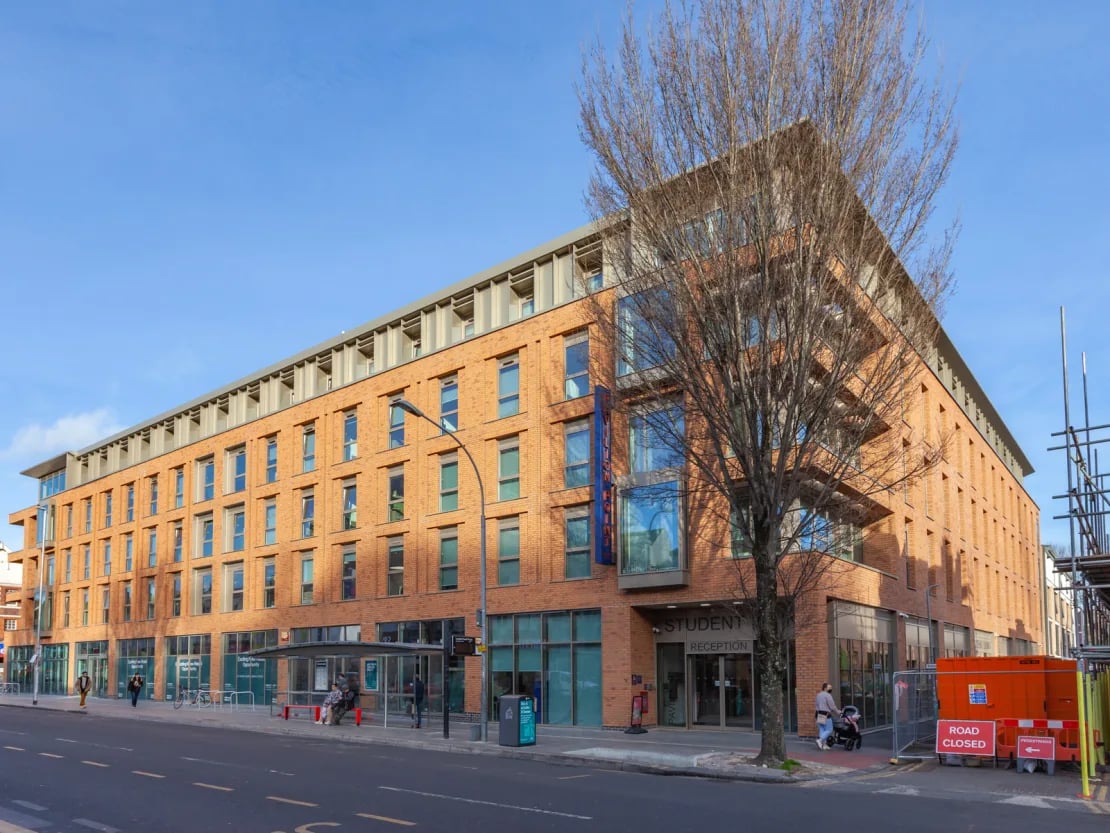 Modern brick building with reception and bus stop exterior at Pavilion Point in Brighton Student Accommodation