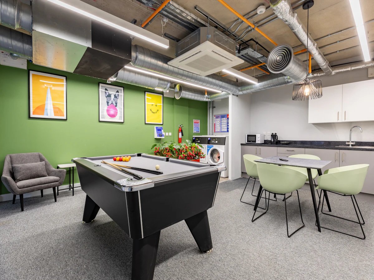 Pool table chairs washing machines kitchen area Common room at Venue Studios in London Student Accommodation
