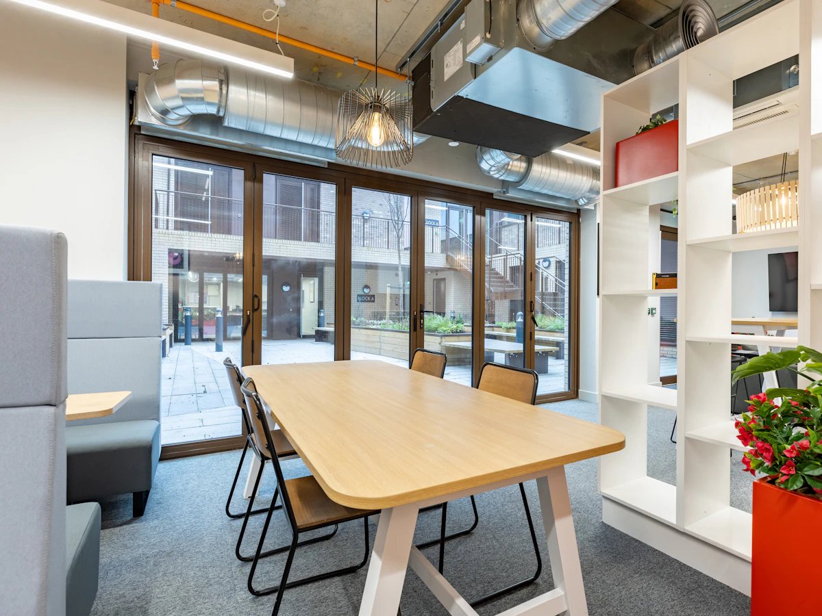 Table chairs shelving and plants communal area at Venue Studios in London Student Accommodation