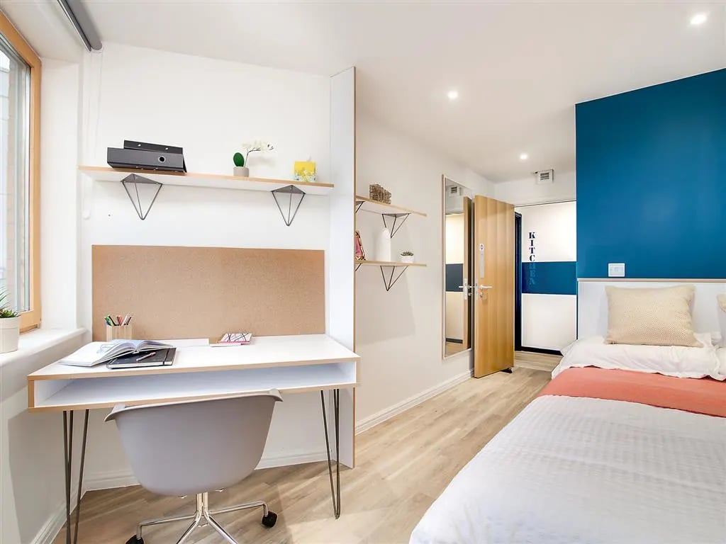Desk chair shelves bed blue wall bedroom at New Orient House in London Student Accommodation