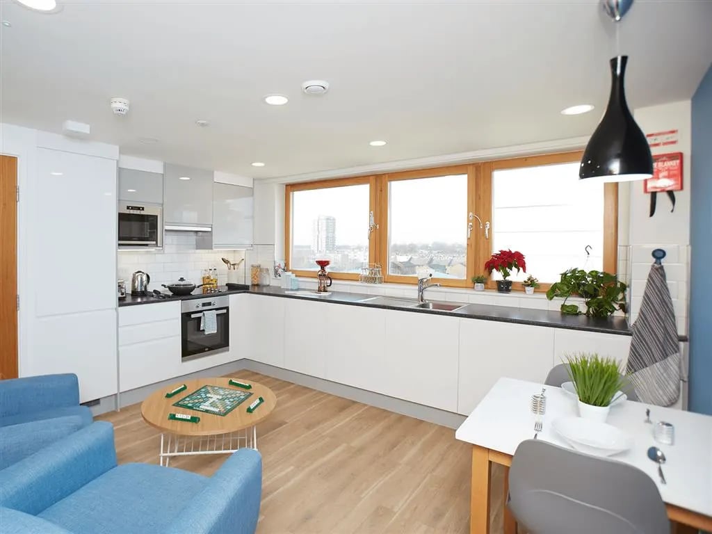 Modern kitchen with blue couches and dining table kitchen at New Orient House in London Student Accommodation