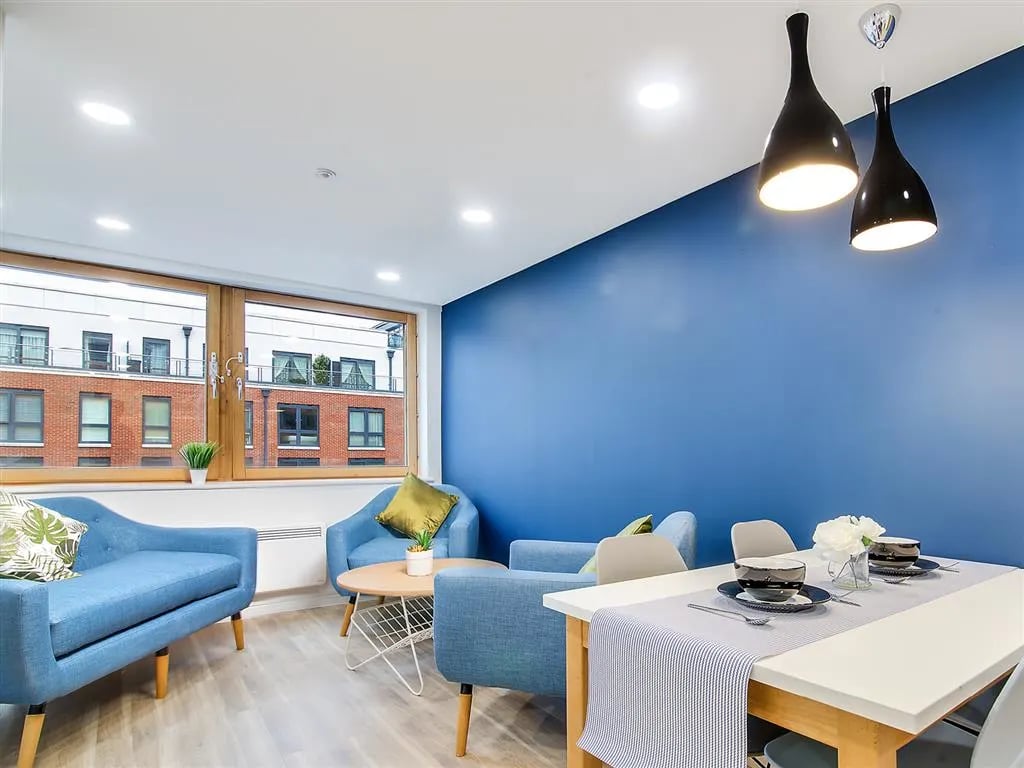 Blue couches dining table and chairs living room at New Orient House in London Student Accommodation