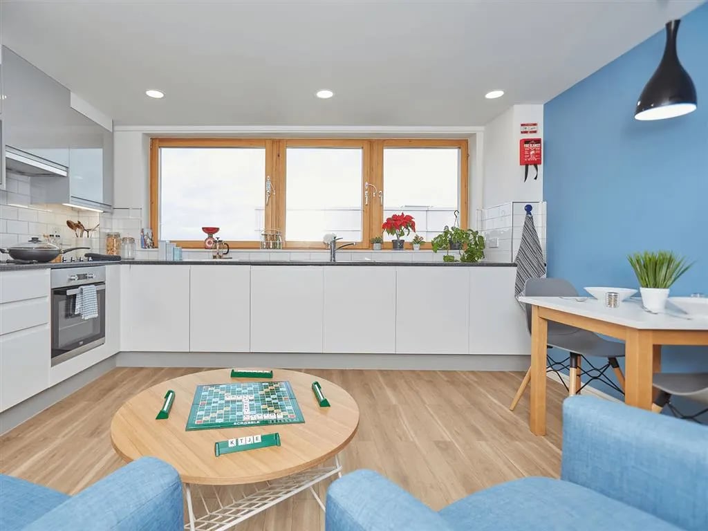Scrabble board table chairs blue kitchen living room at New Orient House in London Student Accommodation