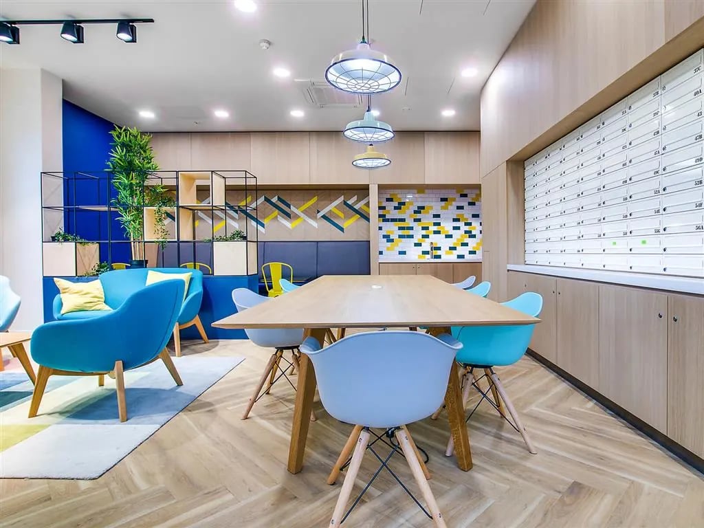 Blue sofas wood table chairs communal area at New Orient House in London Student Accommodation