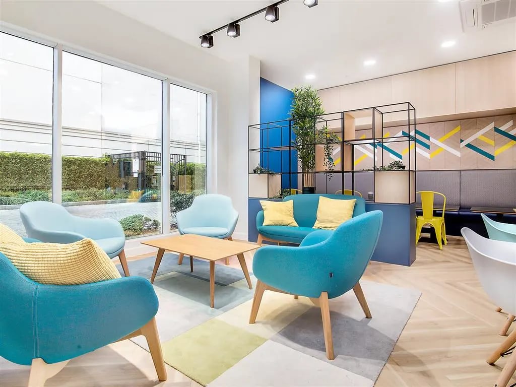 Blue chairs sofa wooden table living area at New Orient House in London Student Accommodation