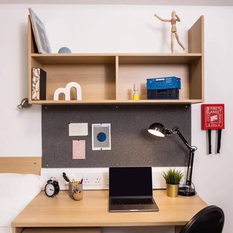 Desk with laptop lamp and shelves study area at Prince Consort Village in London Student Accommodation