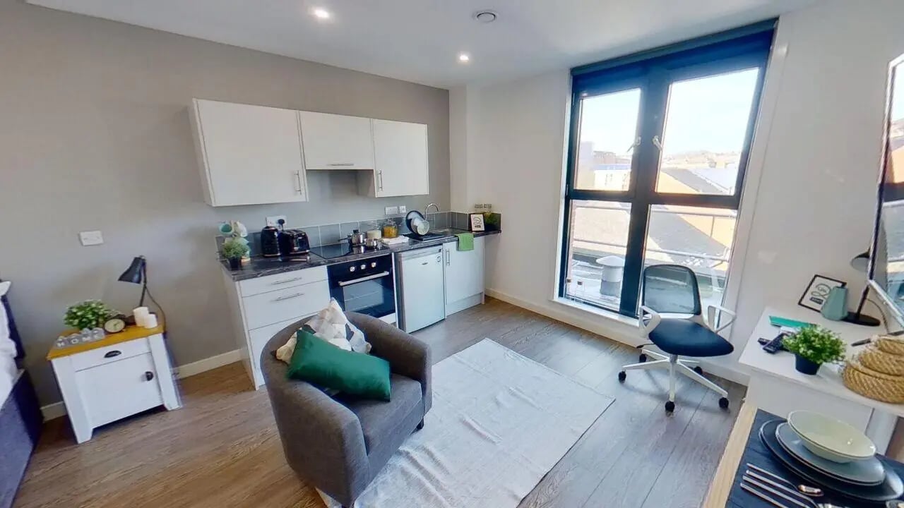 Kitchenette grey armchair desk and window studio apartment at St Marks Court - Nottingham in Nottingham Student Accommodation