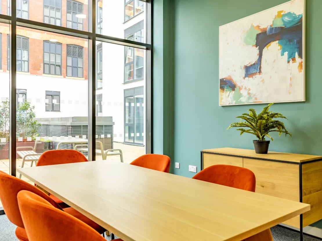 Table with orange chairs painting and plant meeting room at Radford Mill in Nottingham Student Accommodation