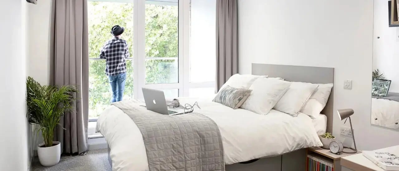 Bed with laptop and balcony view bedroom at Lace Market Studios in Nottingham Student Accommodation