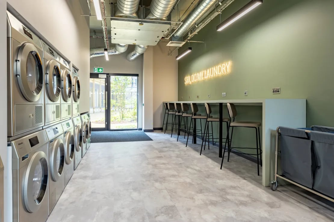 Washing machines seating area and neon sign laundry room at Winfield Court in Nottingham Student Accommodation