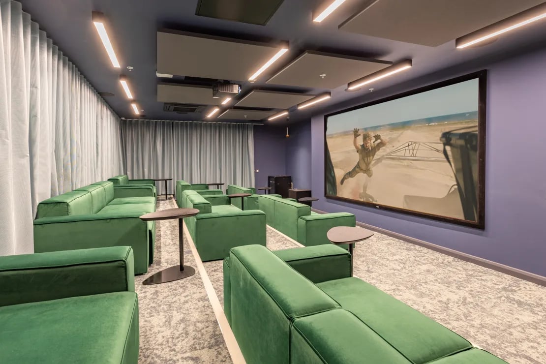 Green couches facing large cinema screen entertainment room at Winfield Court in Nottingham Student Accommodation