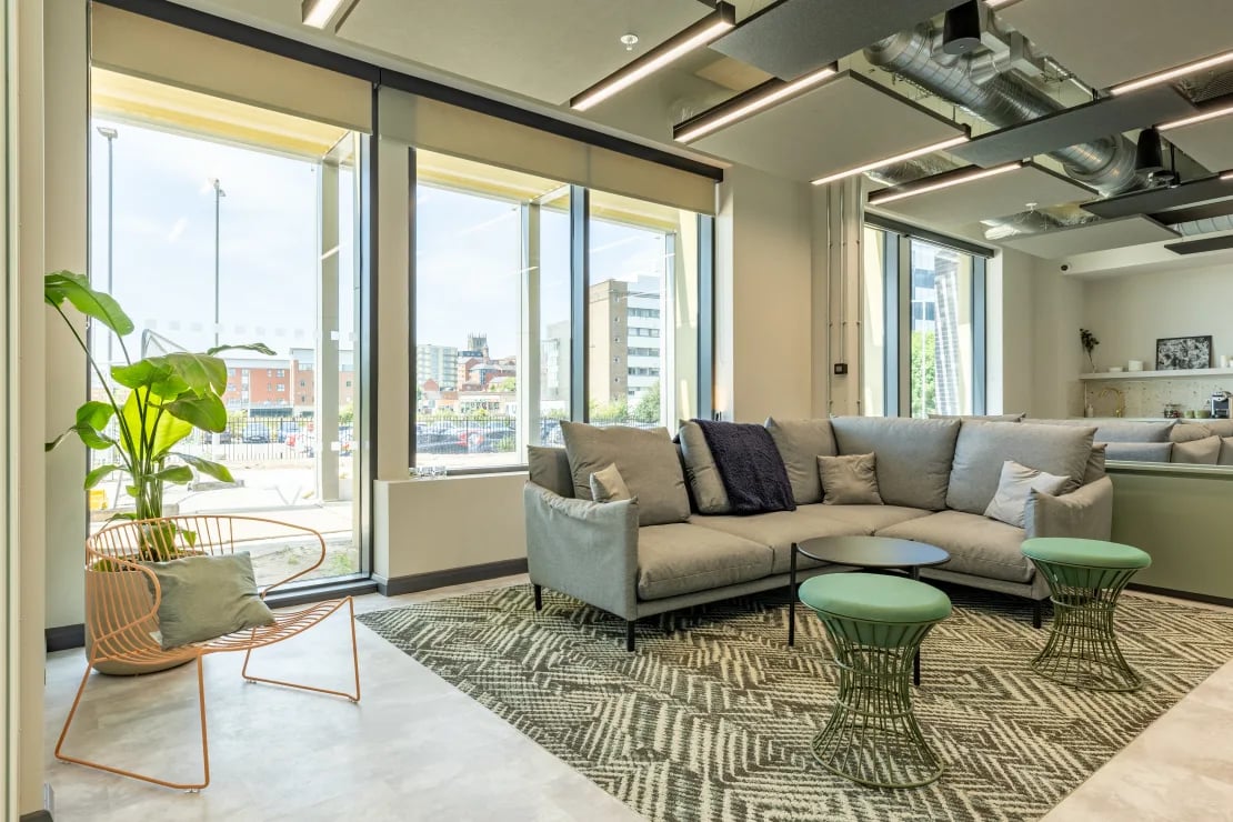 Gray sectional sofa two green stools living room at Winfield Court in Nottingham Student Accommodation