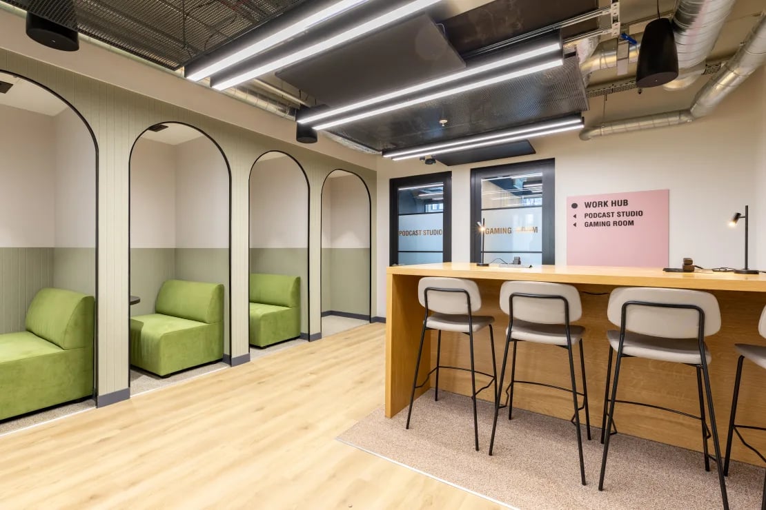 Green sofas under arches counter with stools work hub interior at Winfield Court in Nottingham Student Accommodation