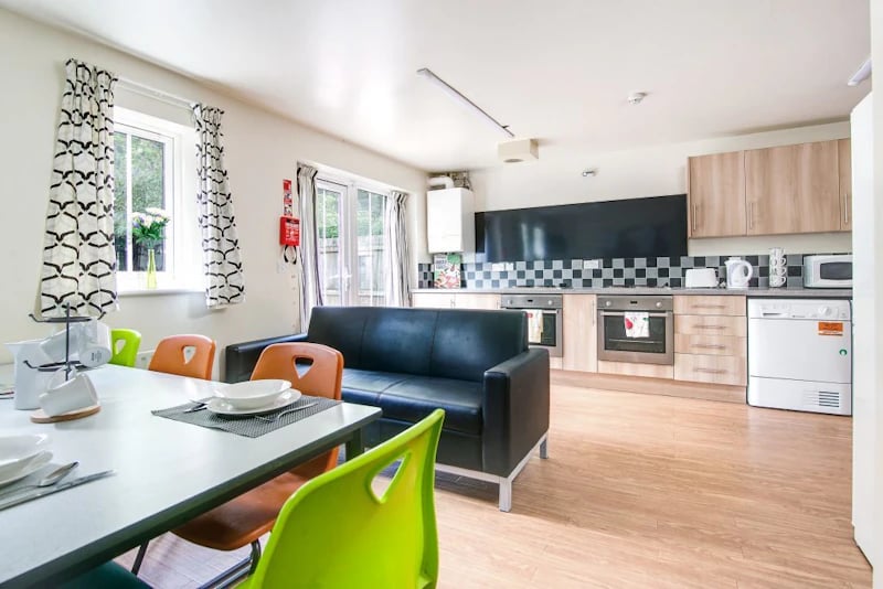 Table chairs sofa and kitchen area living room at Parham Student Village in Canterbury Student Accommodation