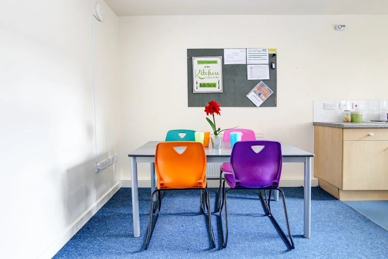 Table with colorful chairs bulletin board kitchen area at Parham Student Village in Canterbury Student Accommodation