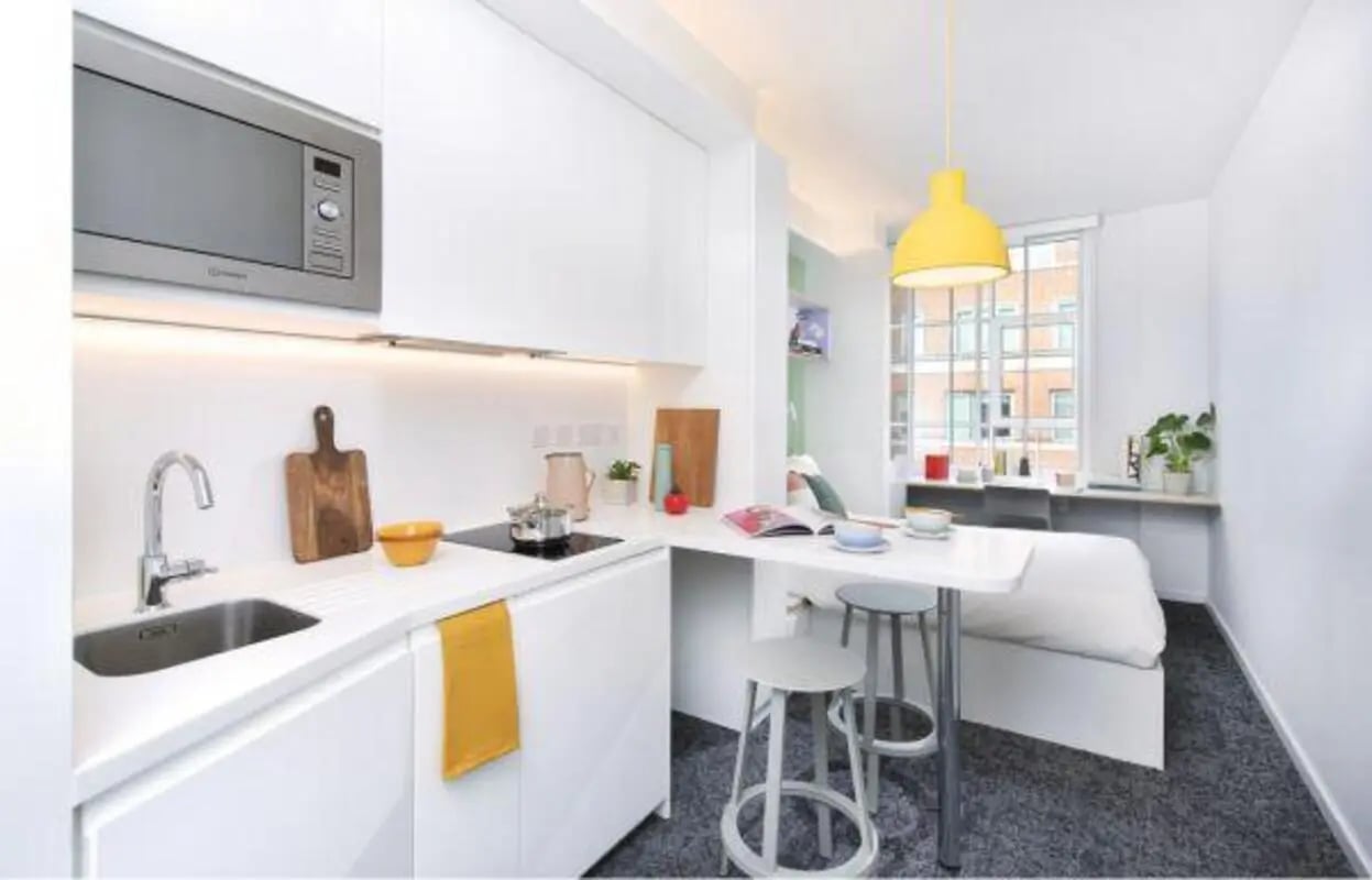 Kitchen and bed area with microwave and stools studio apartment at Scape Bloomsbury in London Student Accommodation