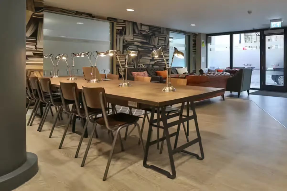 Long table with chairs lamps and sofas communal area at James House in Bath Student Accommodation