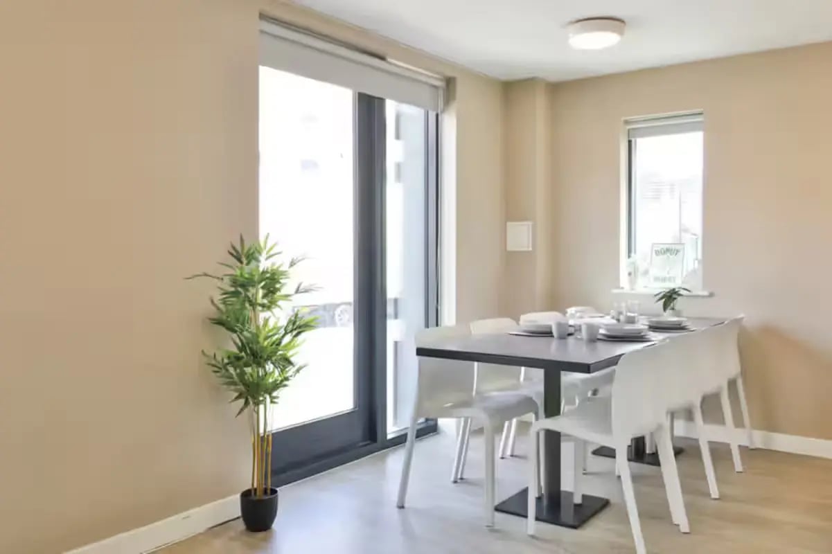 Dining table with chairs plant and large window dining area at James House in Bath Student Accommodation