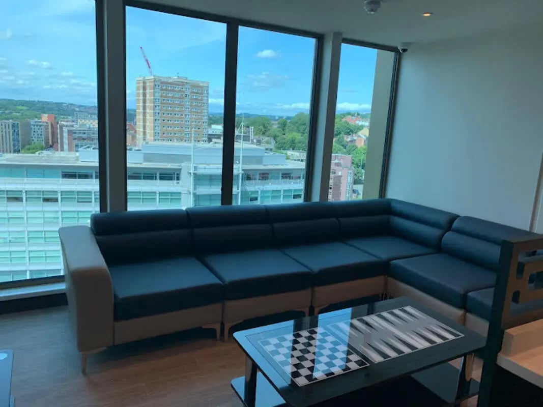 Black sectional sofa and game table living room at Brotherton House in Leeds Student Accommodation