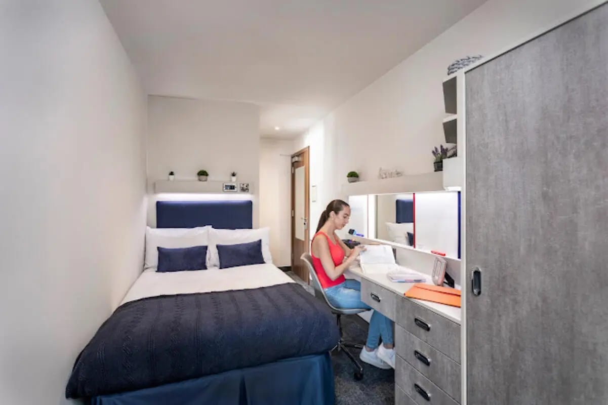 Bed desk and woman studying study area at Brotherton House in Leeds Student Accommodation
