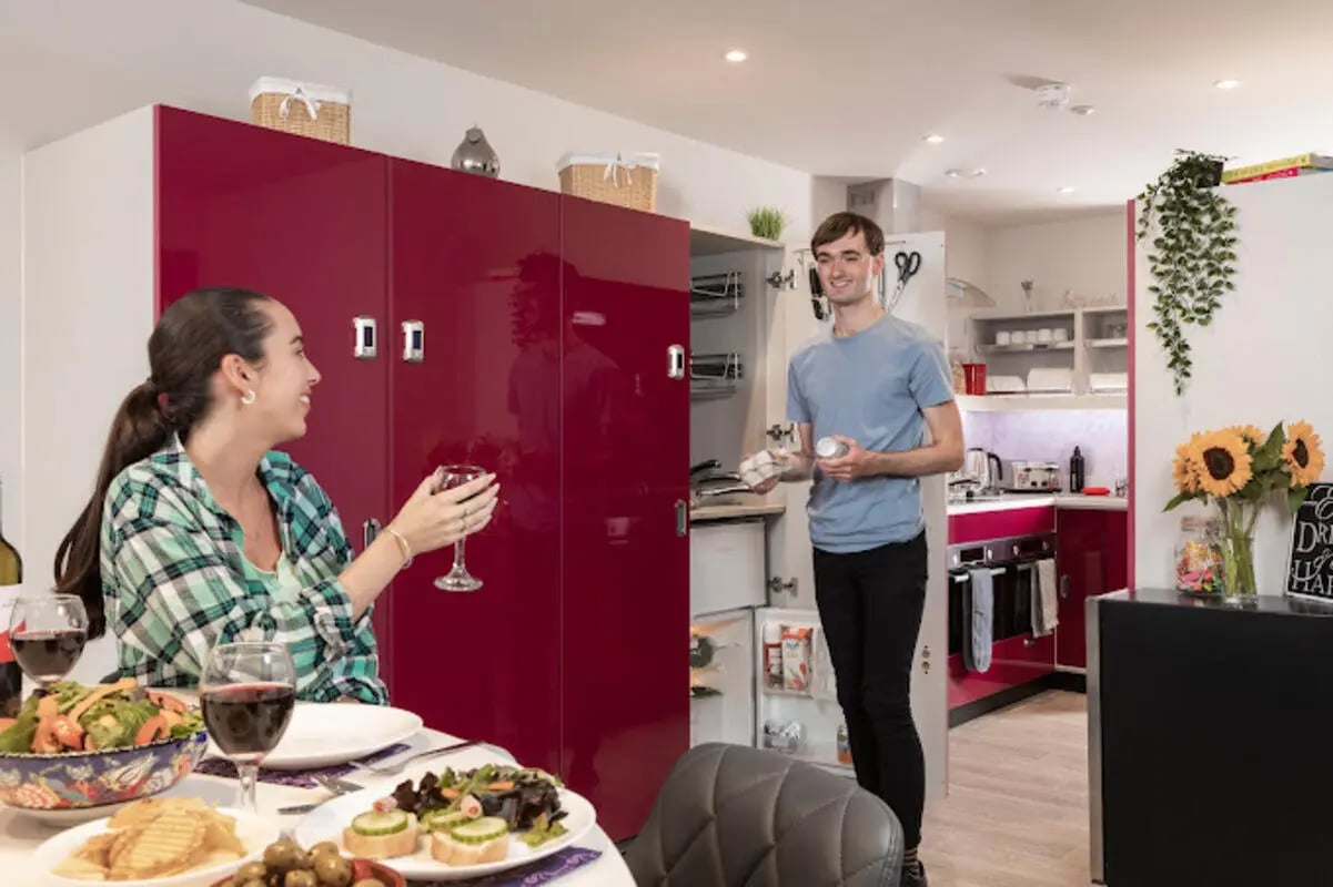Students dine with red cabinets and kitchen exterior at Brotherton House in Leeds Student Accommodation