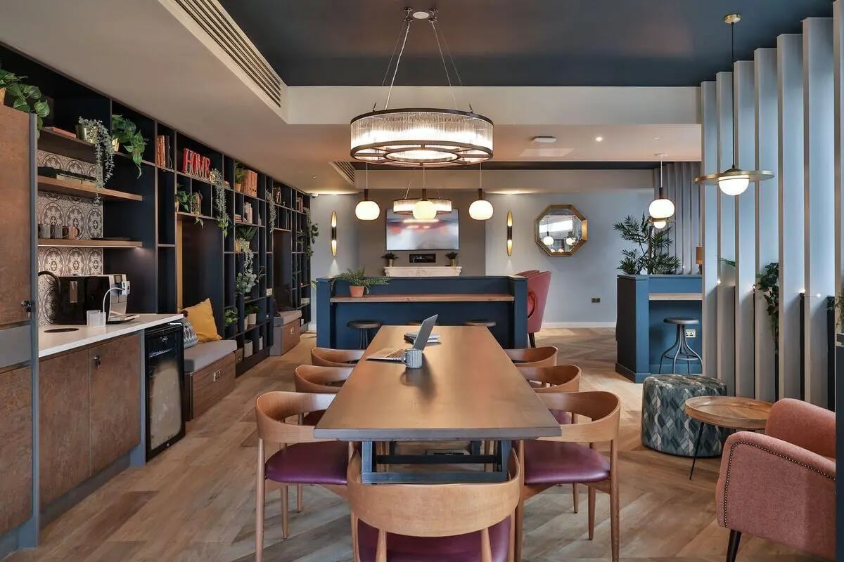 Communal table with chairs, coffee machine, shelves Living room at St Mary's in Bristol Student Accommodation