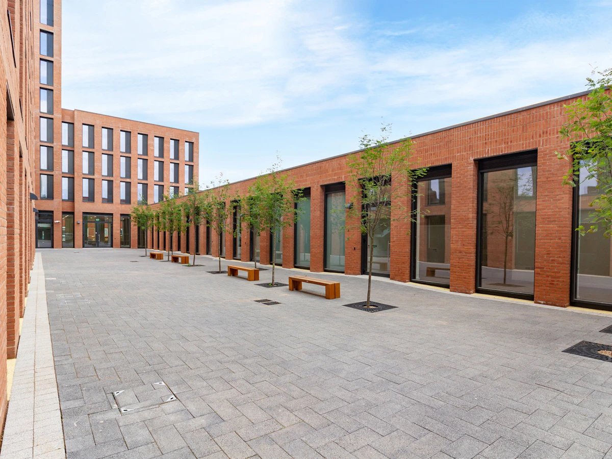 Brick buildings courtyard with benches and trees Exterior at Straits Village in Nottingham Student Accommodation