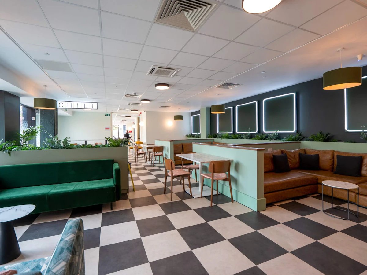 Green and brown sofas tables and chairs common area at Crown Place - Nottingham in Nottingham Student Accommodation