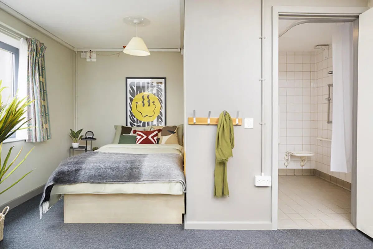 Bed with smiley art and adjacent shower room Bedroom at Lakeside in Birmingham Student Accommodation