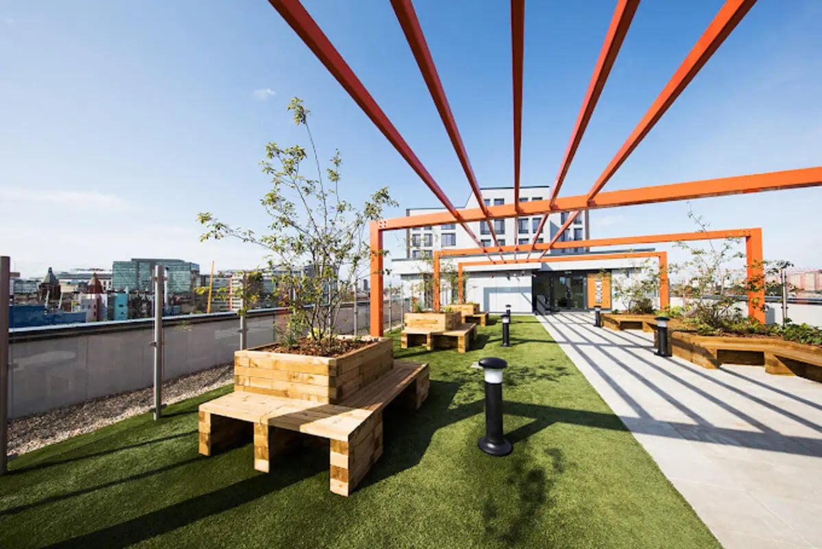 Rooftop benches with plants under orange pergola exterior at Staniforth House in Birmingham Student Accommodation