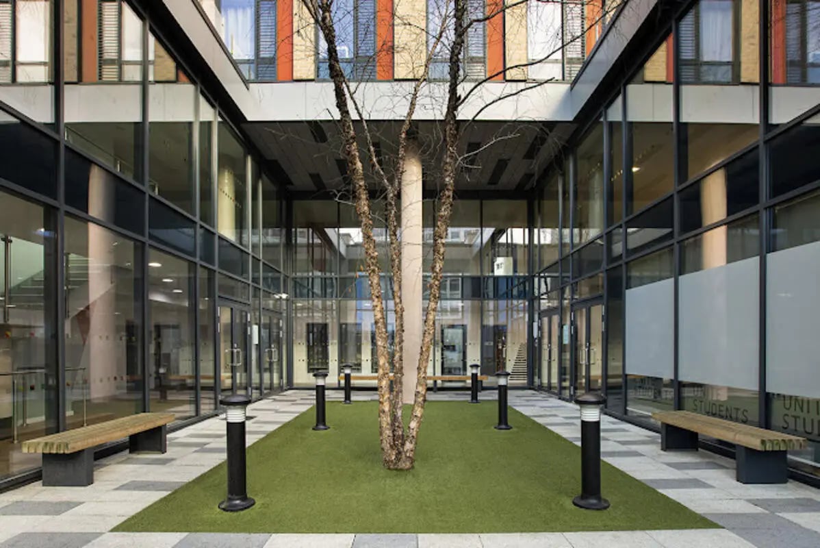 Glass building courtyard with tree and benches courtyard at Staniforth House in Birmingham Student Accommodation
