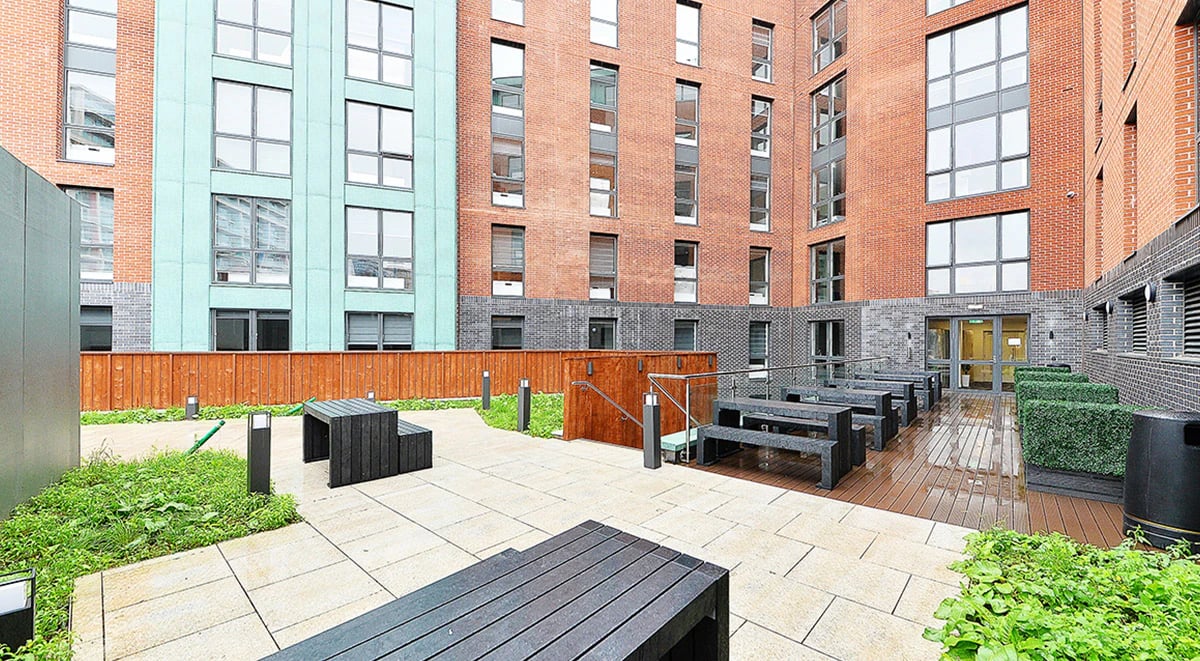 Outdoor seating area with benches and tables exterior at Miura in Nottingham Student Accommodation