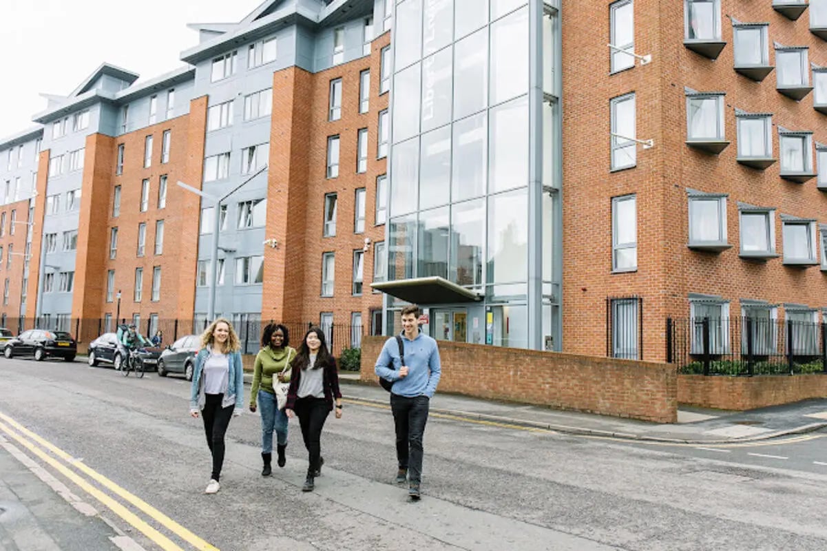 Students walking past brick student accommodation building exterior at Queen's Park House in Coventry Student Accommodation
