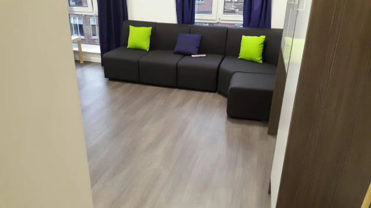 Dark sectional sofa with lime green pillows living room at Queen's Park House in Coventry Student Accommodation