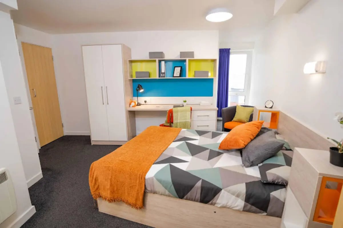 Bed wardrobe desk chair with colorful bedding bedroom at Queen's Park House in Coventry Student Accommodation