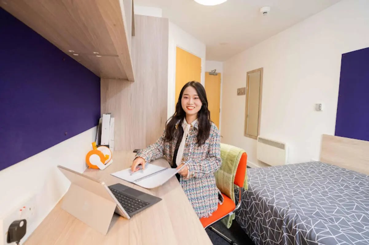 Student at desk with laptop and bed Bedroom at Queen's Park House in Coventry Student Accommodation