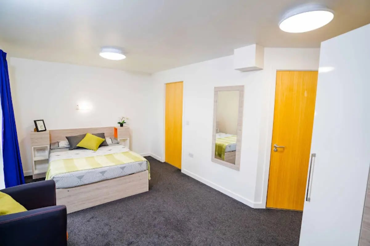 Bed, pillows, picture frame, mirror, yellow door, wardrobe bedroom at Queen's Park House in Coventry Student Accommodation