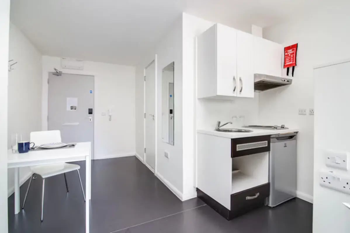 Table chair kitchen counter fridge and fire blanket kitchen at Lucas Studios in Birmingham Student Accommodation