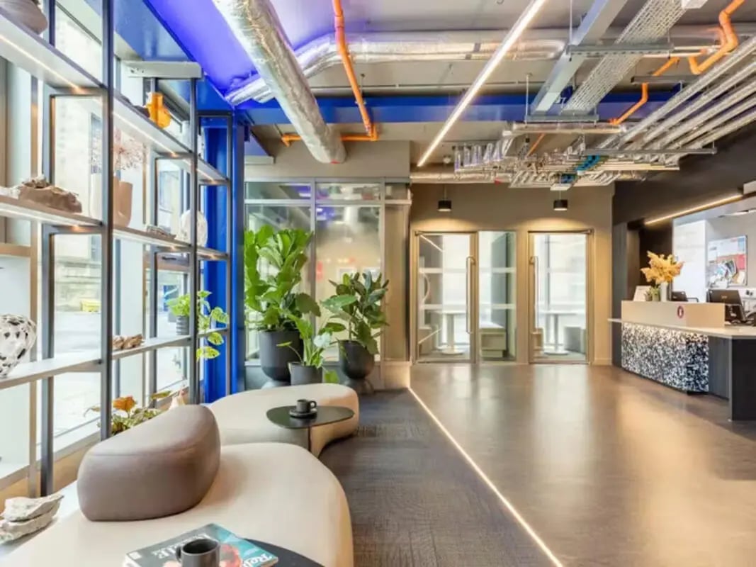 Modern reception area with curved sofa and plants lounge at Potterrow in Edinburgh Student Accommodation