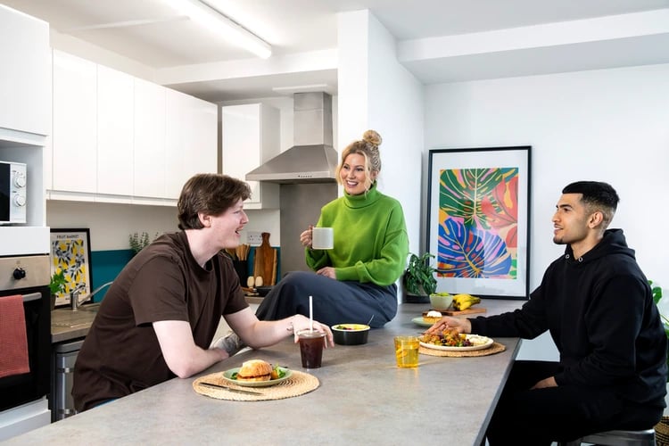 Students eating and talking at kitchen counter kitchen at Castle Court in Leicester Student Accommodation