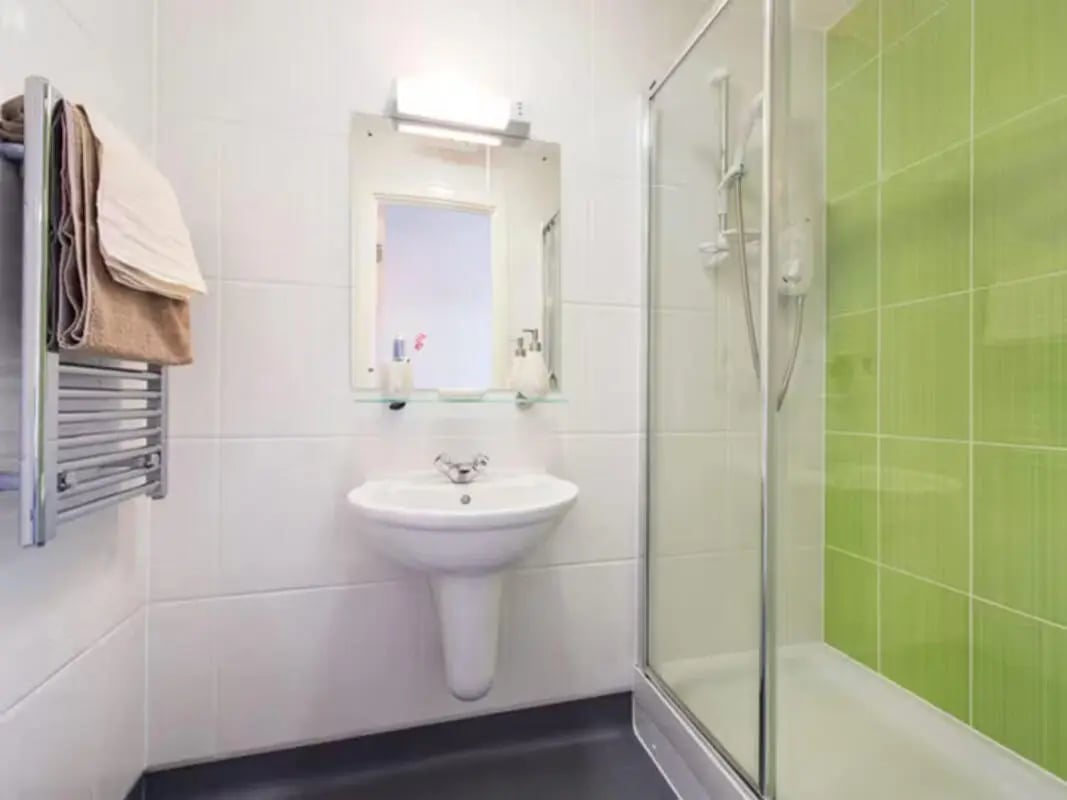 Sink mirror towel rack shower and green tiles bathroom at Ty Ni in Bangor Student Accommodation
